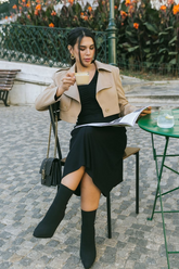 a lady in a long black dress and a crop brown jacket